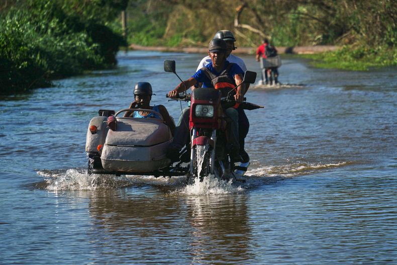Algunas personas transitan por una carretera inundada por el huracán Melissa, el jueves 30 de octubre de 2025, en la costa sur de Santiago de Cuba. (AP Foto/Ramón Espinosa)