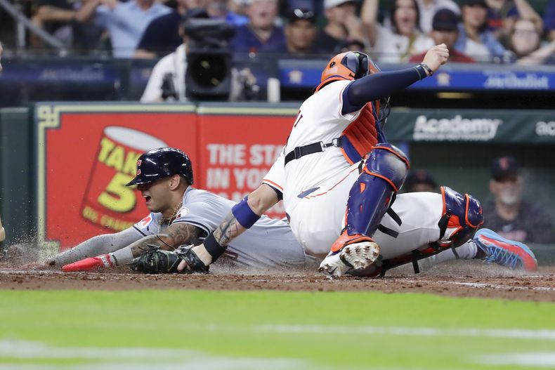El venezolano Brayan Rocchio, de los Guardianes de Cleveland, anota frente al cátcher boricua Víctor Caratini, de los Astros de Houston, el miércoles 1 de mayo de 2024 (AP Foto/Michael Wyke)