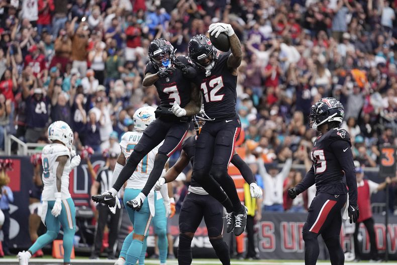 El receptor de los Texans de Houston Nico Collins celebra tras anotar con su compañero Tank Dell en el encuentro ante los Dolphins de Miami el domingo 15 de diciembre del 2024. (AP Foto/Ashley Landis)