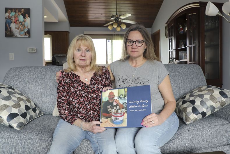 Boni Speer, a la izquierda, y su hija, Tracy Balhan, sostienen una foto de Bill Speer, padre de Tracy, en Aurora, Illinois, el viernes 14 de marzo de 2025. (Benjamin Thorp/WFYI Public Media via AP)