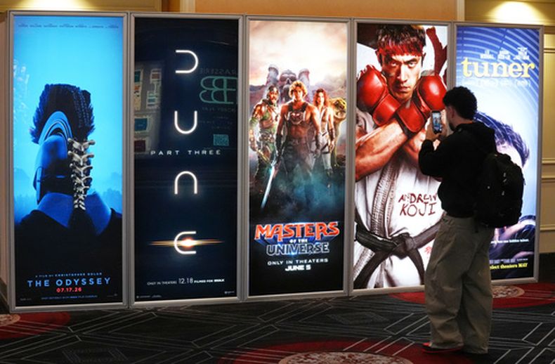 A CinemaCon attendee takes a picture of advertisements for upcoming films during the opening day of CinemaCon 2026, the official convention of Cinema United, on Monday, April 13, 2026, at Caesars Palace in Las Vegas.(Foto AP/Chris Pizzello)