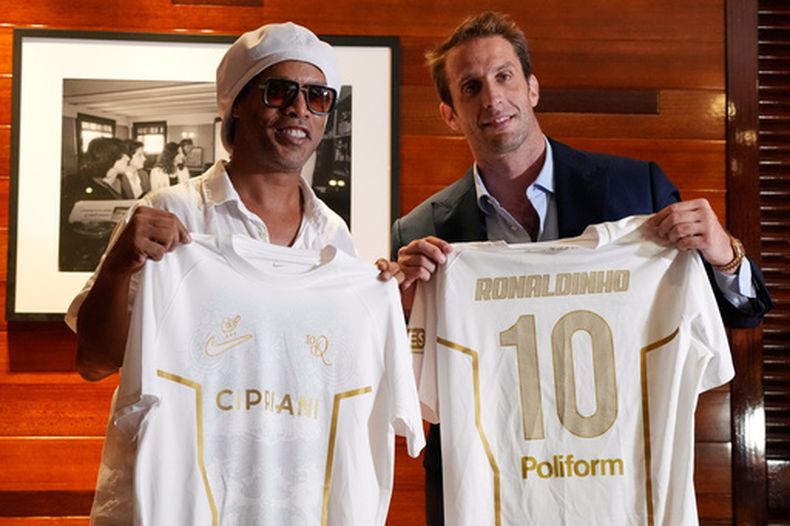 El astro brasileño Ronaldinho sostiene una camiseta del Ravenna FC de la Serie C de Italia junto al presidente del equipo Ignazio Cipriani en la conferencia de prensa para presentarlo como nuevo jugador del club en en el restaurante Cipriani Downtown en Miami el martes 23 de junio del 2026. (AP Foto/Rebecca Blackwell)