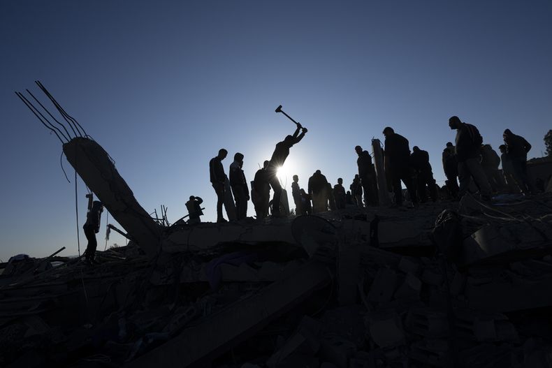 Palestinos buscan cadáveres y sobrevivientes entre los escombros de una casa destruida por un ataque aéreo israelí, el domingo 7 de enero de 2024, en Rafah, en el sur de la Franja de Gaza. (AP Foto/Fatima Shbair)