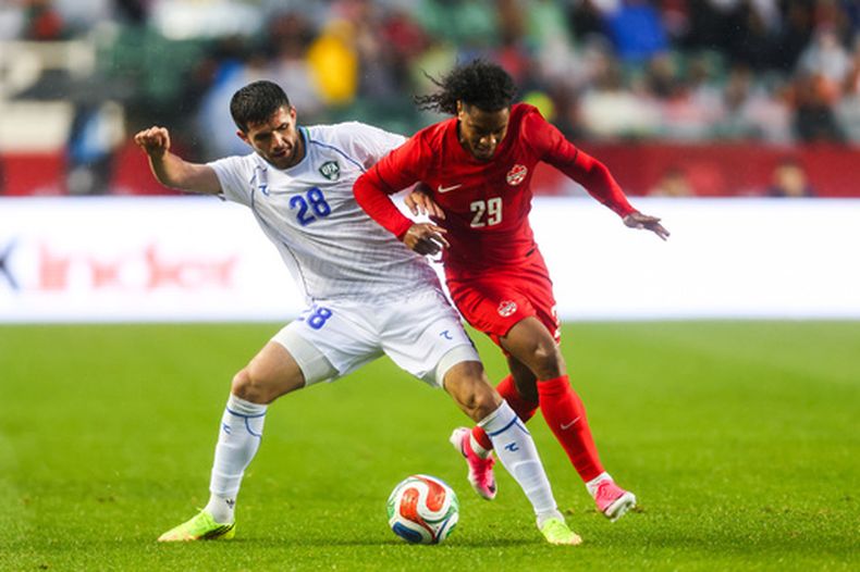 Jayden Nelson (29), de Canadá, disputa un balón con Aziz Amonov (28), de Uzbekistán, durante el segundo tiempo del partido amistoso de preparación rumbo a la Copa del Mundo, el lunes 1 de junio de 2026, en Edmonton, Canadá. (Codie McLachlan/The Canadian Press via AP)