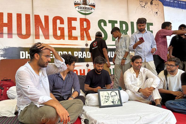 Abhijeet Dipke, fundador del Partido Popular de las Cucarachas (centro, sentado), inicia una huelga de hambre indefinida durante una protesta para exigir la renuncia del ministro de Educación Dharmendra Pradhan por supuestas irregularidades en exámenes y filtraciones, en Nueva Delhi, India, el 18 de julio de 2026. (AP Foto/Shonal Ganguly)