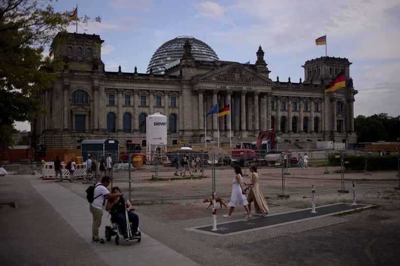 Varias personas caminan frente al edificio del Reichstag --el Parlamento alemán-- el viernes 2 de mayo de 2025, en Berlín, Alemania. (AP Foto/Markus Schreiber)