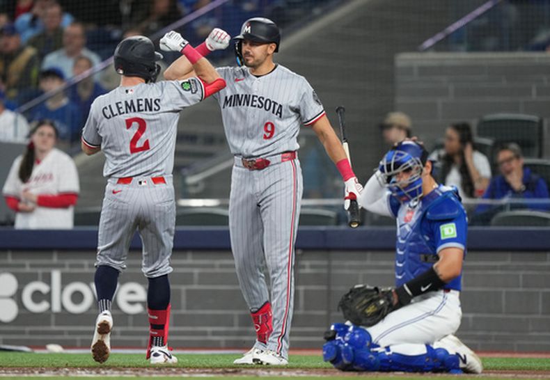 Kody Clemens (2) celebra con su compañero de equipo Trevor Larnach (9) tras conectar un jonrón solitario durante la acción de la tercera entrada de un juego de béisbol contra los Azulejos de Toronto, en Toronto, el domingo 12 de abril de 2026. (Nathan Denette/The Canadian Press vía AP)