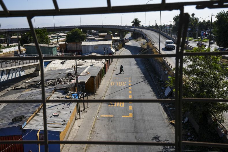 Un peatón cruza una calle en la zona donde fue encontrado el cuerpo del exmilitar venezolano Ronald Ojeda, durante un operativo policial contra la organización criminal venezolana Tren de Aragua en Santiago, Chile, el miércoles 1 de enero de 2025. (AP Foto/Esteban Felix)