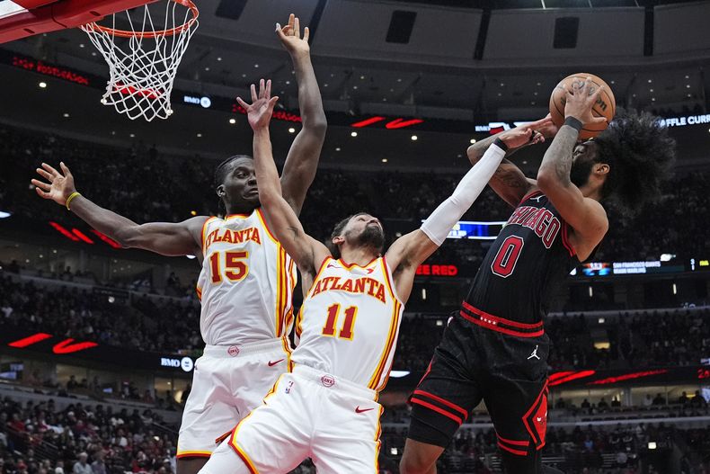 Coby White, base de los Bulls de Chicago, dispara frente a Trae Young (centro) y Clint Capela, de los Hawks de Atlanta, en el minitorneo de repesca de la NBA, el miércoles 17 de abril de 2024 (AP Foto/Nam Y. Huh)