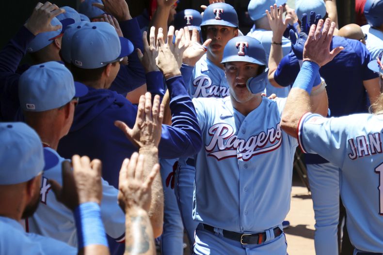 Josh Jung, de los Rangers de Texas, es felicitado en el dugout después de conectar un grand slam en contra de los Yanquis de Nueva York en la primera entrada durante el juego de béisbol el domingo 30 de abril de 2023, en Arlington, Texas. (AP Foto/Richard W. Rodriguez)