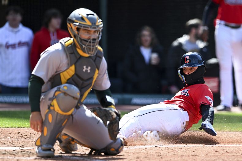 Andrés Giménez, derecha, de los Guardianes de Cleveland, anota con doblete de Josh Naylor durante la séptima entrada en el juego de béisbol en contra de los Atléticos de Oakland, el ddomingo 21 de abril de 2024, en Cleveland. (AP Foto/Nick Cammett)