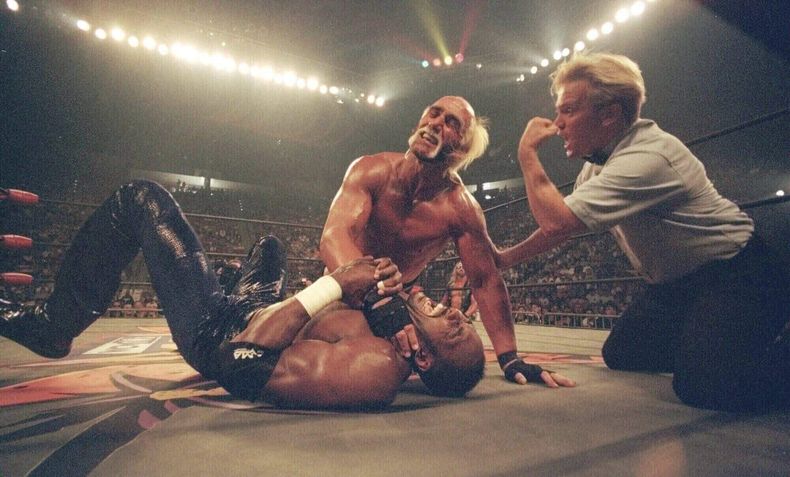 ARCHIVO - Hollywood Hulk Hogan le pone una llave de estrangulamiento al cuello a la estrella de baloncesto de Utah Jazz, Karl Malone, en un combate de lucha libre de pago por evento el 12 de julio de 1998, en San Diego. (Foto AP/Lenny Ignelzi, archivo)
