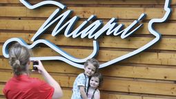 Aaron Mart, de 4 años, y su hermana Eloise, de 2, cuyo padre es ingeniero del equipo Rede Bull, se sacan una foto por su madre Anne Bachelay frente al logo del Gran Premio de Miami de la Fórmula Uno, el jueves 1 de mayo de 2025, en Miami Gardens, Florida.. (AP Foto/Rebecca Blackwell)