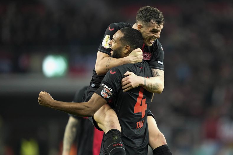 Jonathan Tah, y su compañero del Bayer Leverkusen Granit Xhaka celebran luego del partido de cuartos de final de la Copa de Alemania ante el VfB Stuttgart, en el BayArena, en Leverkusen, Alemania, el martes 6 de febrero de 2024. (AP Foto/Martin Meissner)