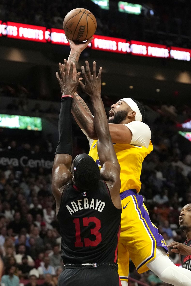 Anthony Davis, derecha, de los Lakers de Los Ángeles, dispara sobre Bam Adebayo (13), del Heat de Miami, durante la primera mitad del juego de baloncesto de la NBA, el lunes 6 de noviembre de 2023, en Miami. (AP Foto/Lynne Sladky)