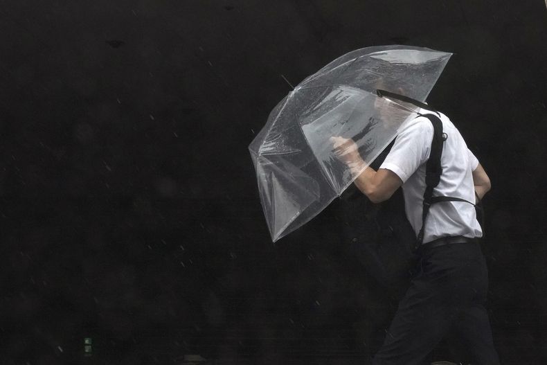 Una persona sostiene un paraguas contra el fuerte viento y la lluvia mientras camina por una calle de Tokio el viernes 2 de junio de 2023. (Foto AP/Eugene Hoshiko)