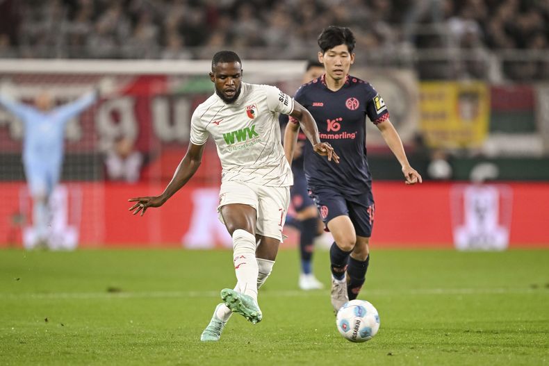 Hyunseok Hong del Mainz y Frank Onyeka del Augsburg batallan por el balón en el encuentro de la Bundesliga el viernes 20 de septiembre del 2024. (Harry Langer/dpa via AP)
