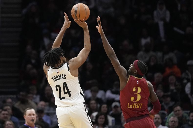 El armador de los Nets de Brooklyn Cam Thomas (24) realiza un tiro sobre el base de los Cavaliers de Cleveland Caris LeVert (3) en la segunda mitad del juego de baloncesto de la NBA, el domingo 10 de marzo de 2024, en Cleveland. (AP Foto/Sue Ogrocki)