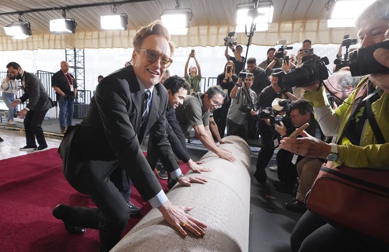 Conan OBrien, presentador de la 97ª edición de los Premios de la Academia del domingo, ayuda a desenrollar la alfombra roja para el espectáculo en el Dolby Theatre el miércoles 26 de febrero de 2025 en Los Ángeles. (Foto AP/Chris Pizzello)