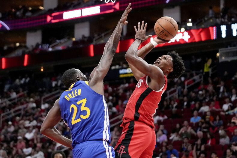 El alero de los Rockets de Houston, Amen Thompson, a la derecha, dispara mientras el alero de los Warriors de Golden State, Draymond Green, defiende durante la primera mitad el sábado 2 de noviembre de 2024, en Houston. (AP Foto/Eric Christian Smith)