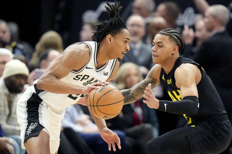 Devin Vassell, base de los Spurs de San Antonio, avanza frente a Keyonte George, del Jazz de Utah, el miércoles 27 de marzo de 2024 (AP Foto/Rick Bowmer)