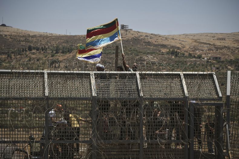 Drusos sirios protestan cerca de la frontera sirio-israelí, vistos desde la localidad de Majdal Shams en la región controlada por Israel de los Altos del Golán, el miércoles 16 de julio de 2025, entre combates entre fuerzas sirias y grupos armados drusos en la ciudad siria de Sweida. (AP Foto/Leo Correa)