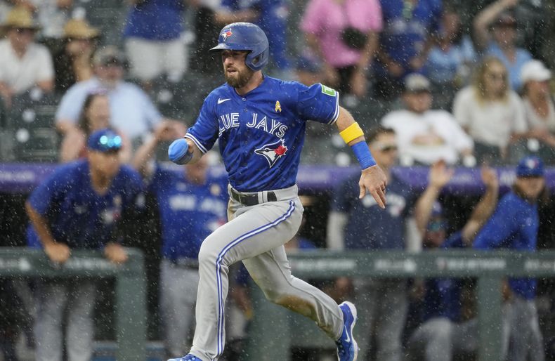 El corredor emergente Mason McCoy anota la carrera de la ventaja gracias a un sencillo de Whit Merrifield en contra del relevista de los Rockies de Colorado Justin Lawrence en la novena entrada en el juego de béisbol del domingo 3 de septiembre de 2023, en Denver. (AP Foto/David Zalubowski)