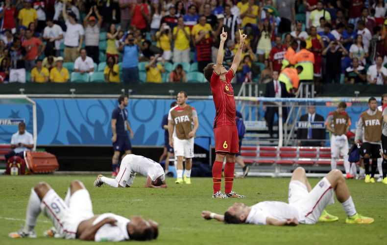 El belga Axel Witsel celebra al final de la pr&oacute;rroga, mientras los jugadores estadounidenses yacen exhaustos y decepcionados, en un duelo de octavos de final de la Copa del Mundo, realizado el martes 1 de julio de 2014, en Salvador, Brasil (AP Foto