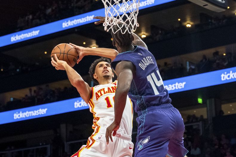 Zaccharie Risacher (10), de los Hawks de Atlanta, ataca el aro contra Moussa Diabate (14), de los Hornets de Charlotte, durante la primera mitad del juego de baloncesto de la NBA. el viernes 25 de 2024, en Atlanta. (AP Foto/Jason Allen)