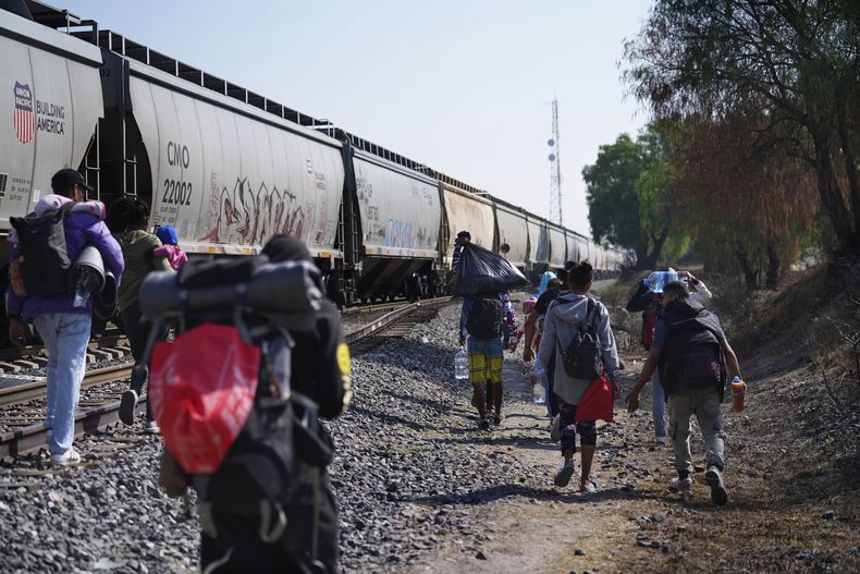 Migrantes caminan junto a un tren con dirección al norte, esperando poder subirse a él, en Huehuetoca, México, el viernes 12 de mayo de 2023. (AP Foto/Marco Ugarte)