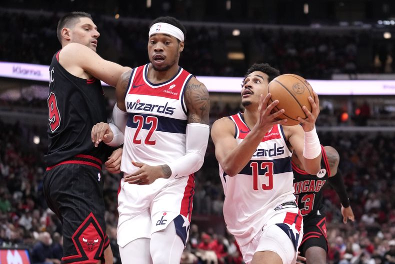 Jordan Poole, de los Wizards de Washington, se enfila a la canasta con una pantalla colocada sobre Nikola Vucevic (9), de los Bulls de Chicago, de Richaun Holmes durante la primera mitad del juego de baloncesto de la NBA, el lunes 25 de marzo de 2024, en Chicago. (AP Foto/Charles Rex Arbogast)