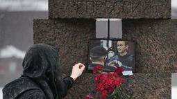 Una mujer toca la fotografía de Alexei Navalny tras dejar flores en homenaje al fallecido líder opositor ruso, en San Petersburgo, Rusia, el sábado 17 de febrero de 2024. (AP Foto/Dmitri Lovetsky)