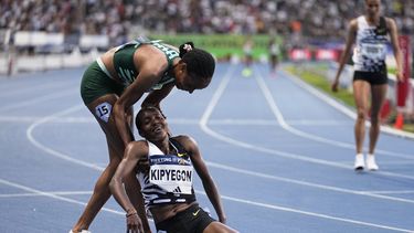 La keniana Faith Kipyegon recibe ayuda para ponerse de pie por parte de la también keniana Beatrice Chepkoech (izquierda) tras ganar los 5.000 metros y batir el récord mundial en la justa de París de la Liga Diamante, el viernes 9 de junio de 2023. (AP Foto/Michel Euler)