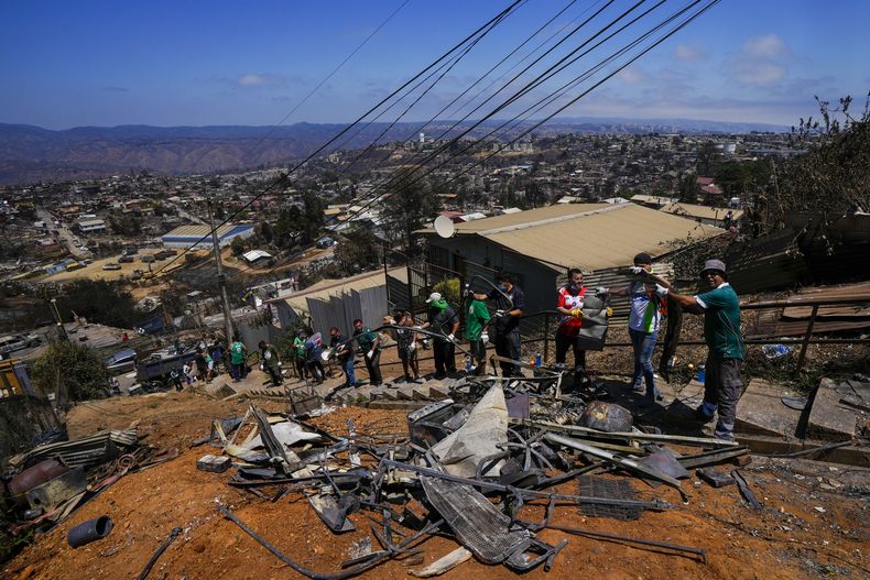 Aficionados del club de fútbol Wanders hacen labores voluntarias de limpieza en un área afectada por incendios forestales en el vecindario Villa Independencia, el martes 6 de febrero de 2024, en Viña del Mar, Chile. (AP Foto/Esteban Félix)