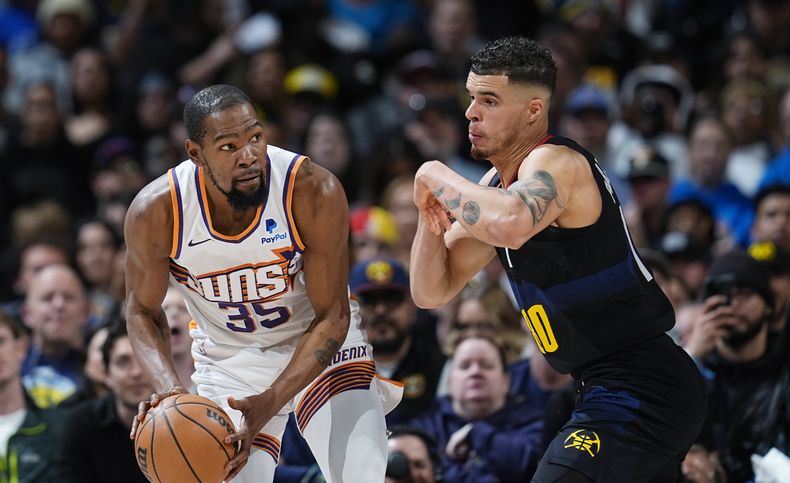 Kevin Durant, alero de los Suns de Phoenix, busca avanzar frente a Michael Porter Jr., de los Nuggets de Denver, en el duelo del miércoles 27 de marzo de 2024 (AP Foto/David Zalubowski)