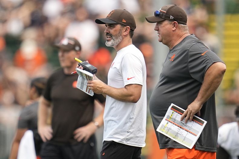 El entrenador de los Browns de Cleveland Kevin Stefanski (izquierda) y el coordinador ofensivo Alex Van Pelt (derecha) conversan durante el campo de prácticas de la NFL, en Berea, Ohio. Martes 1 de agosto de 2023. (AP Foto/Sue Ogrocki)