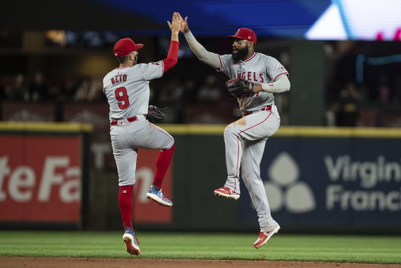 Zach Neto, izquierda, y Jo Adell, de los Angelinos de Los Ángeles, celebran después de vencer a los Marineros de Seattle, el lunes 22 de julio de 2024, en Seattle. (AP Foto/Stephen Brashear)