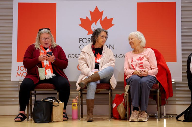 Tres personas esperan el resultado de una consulta sobre la independencia de Alberta en un evento de partidarios de permanecer en Canadá, en Edmonton, Alberta, el 19 de octubre de 2026. (James Maclennan/The Canadian Press via AP)
