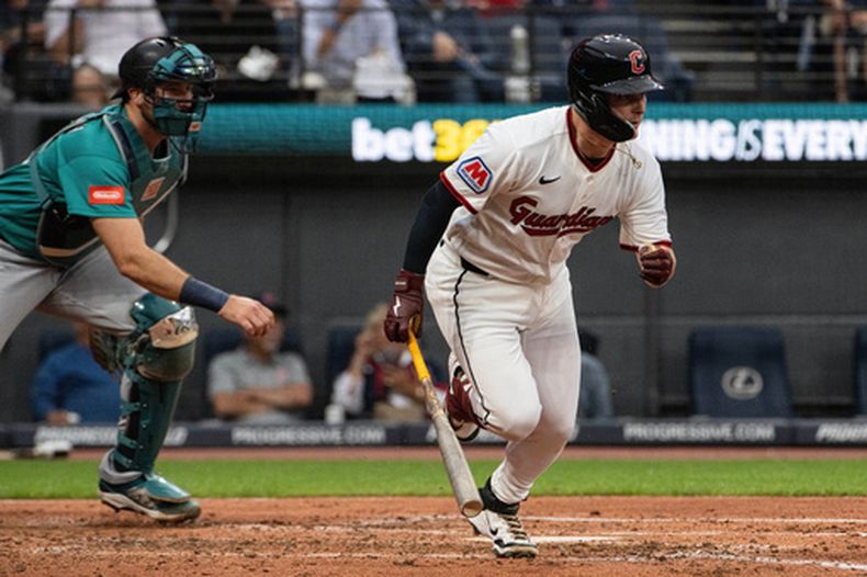 Cooper Ingle, de los Guardianes de Cleveland, observa su primer imparable en Grandes Ligas, un sencillo productor de dos carreras ante Logan Gilbert, lanzador de los Marineros de Seattle, mientras el receptor Cal Raleigh observa al fondo durante la tercera entrada del juego de béisbol de Grandes Ligas, el sábado 27 de junio de 2026, en Cleveland. (AP Foto/Phil Long)