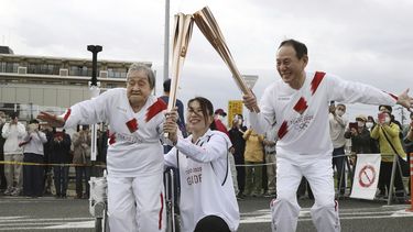 Shigeko Kagawa, a la izquierda, entrega la antorcha olímpica al siguiente corredor durante el relevo de la llama de los Juegos Olímpicos de Tokio, en Yamatokooriyama, Japón, el 12 de abril de 2021. Kagawa, una médica jubilada de 114 años, es la persona viva más anciana de Japón, se informó el 4 de agosto de 2025. (Kyodo News vía AP)