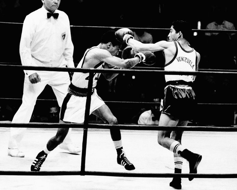 ARCHIVO - El boxeador venezolano Francisco Rodríguez (derecha) conecta de zurda al estadounidense durante la pelea de peso minimosca en los Juegos Olímpicos de México, el 25 de octubre de 1968. Francisco Morochito Rodríguez, quien en esos Juegos ganó el primer oro olímpico de Venezuela, ha fallecido. Tenía 78 años. (AP Foto)