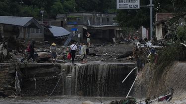 Varias personas caminan en un poblado dañado por inundaciones en el distrito Mentougou, el lunes 31 de julio de 2023, en Beijing, China. (AP Foto/Andy Wong)
