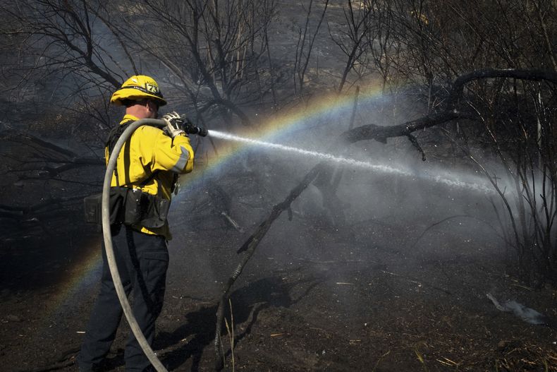 Un bombero rocía con agua parte de la zona arrasada por el incendio Archer, en Granada Hills, Los Ángeles, el 10 de enero de 2025. (AP Foto/Ethan Swope)