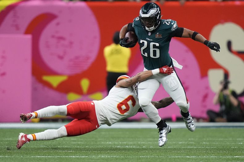 Saquon Barkley (26), corredor de los Eagles de Filadelfia, intenta eludir la tacleadade Bryan Cook (6), safety de los Chiefs de Kansas City, durante la primera mitad del Super Bowl 59 de la NFL, el domingo 9 de febrero de 2025, en Nueva Orleans. (AP Foto/Frank Franklin II)