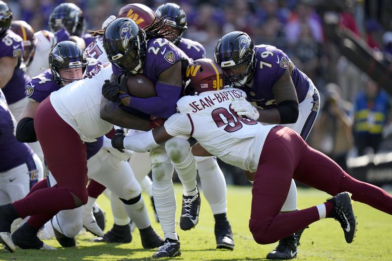 Derrick Henry (22), running back de los Ravens de Baltimore, corre con el balón en contra de los Commanders de Washington, con Javontae Jean-Baptiste (90) tratando de detenerlo durante la segunda mitad del partido de la NFL, el domingo 13 de octubre de 2024, en Baltimore. (AP Foto/Stephanie Scarbrough)