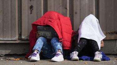ARCHIVO - Niños se cubren la cabeza mientras están sentados afuera de un refugio para migrantes, el miércoles 13 de marzo de 2024, en Chicago. (AP Foto/Erin Hooley, Archivo)