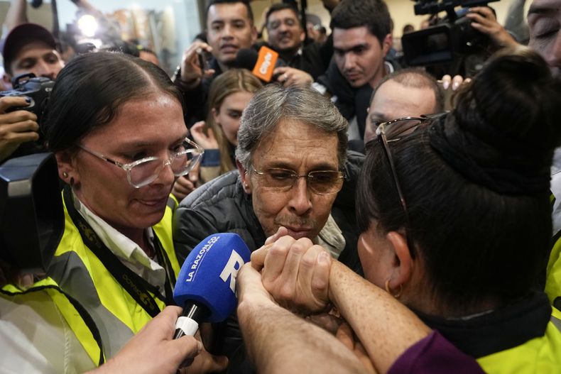 Fabio Ochoa, al centro, exmiembro del cártel de Medellín, besa la mano de un familiar a su llegada al aeropuerto El Dorado, tras ser deportado de EEUU, en Bogotá, Colombia, el 23 de diciembre de 2024. (AP Foto/Fernando Vergara)