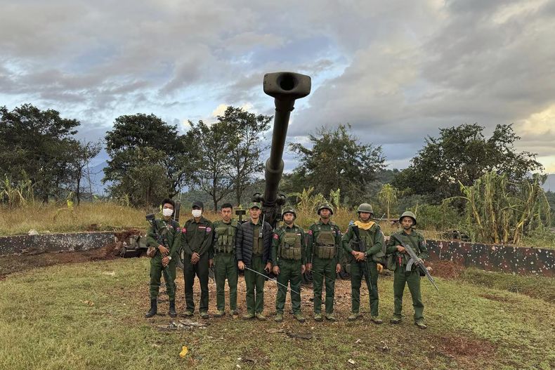 En esta foto facilitada por el medio de comunicación digital Kokang Media, miembros de un grupo de fuerzas armadas étnicas, una de las tres milicias conocidas como la Alianza de las Tres Hermandades, posan para una fotografía delante de las armas que el grupo supuestamente arrebató al puesto de avanzada del ejército de Myanmar en una colina del municipio de Hsenwi, el 24 de noviembre de 2023, estado de Shan, Myanmar. (Kokang Media via AP)