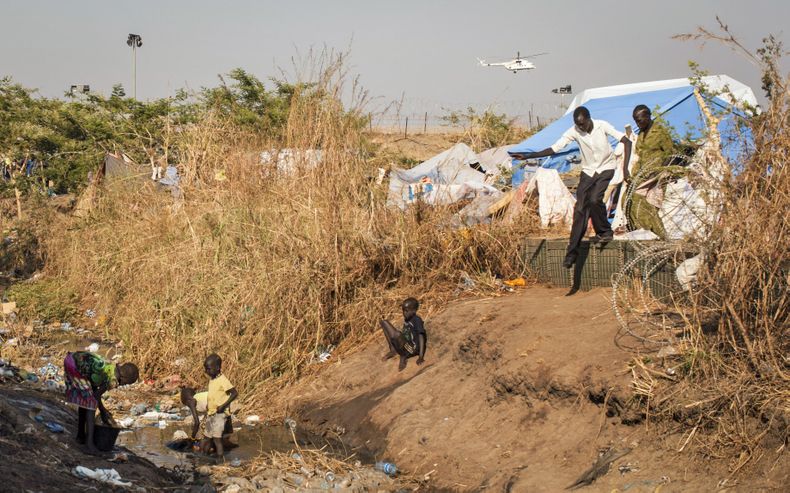 Ni&ntilde;os lavan sus ropas en un arroyo de aguas f&eacute;tidas que atraviesa un campamento para desplazados por la violencia en Juga, capital de Sud&aacute;n del Sur, el s&aacute;bado 11 de enero de 2014. Al fondo un helic&oacute;ptero de Naciones Unid