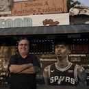 El empresario y seguidor de los Spurs de San Antonio Roland Ramirez posa con el mural del francés Victor Wembanyama que realizó el artista Nik Soupe afuera de su restaurante de mariscos en San Antonio el jueves 15 de junio del 2023. (AP Foto/Eric Gay)